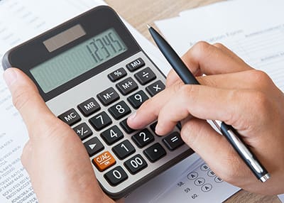 person typing numbers into a calculator