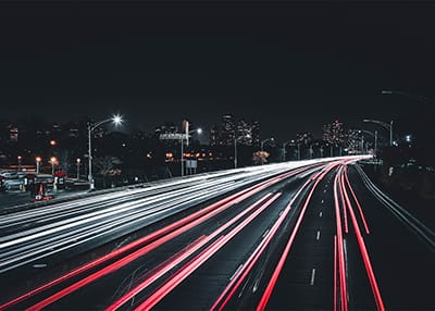 cars driving down highway at night